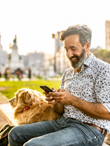 Man on bench with dog on phone