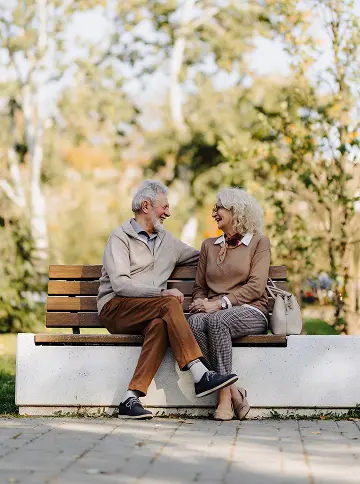 Couple sitting on park bench facing each other